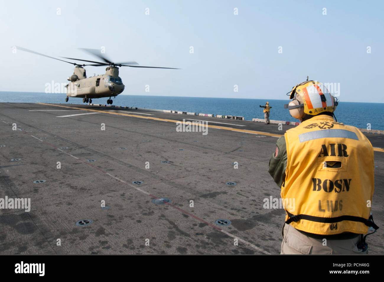 A U.S. Sailor directs an Army CH-47F Chinook helicopter assigned to the 3rd General Support Aviation Battalion, 2nd Combat Aviation Brigade, 2nd Infantry Division to land aboard the amphibious assault ship USS Bonhomme Richard (LHD 6) in the East China Sea April 11, 2014. The Bonhomme Richard was underway in the U.S. 7th Fleet area of responsibility supporting maritime security operations and theater security cooperation efforts. Stock Photo