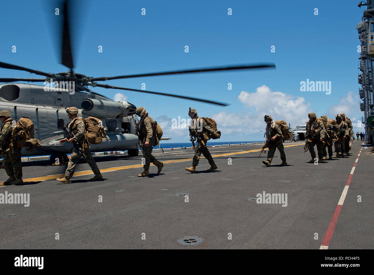 Marines assigned to the 3rd Battalion, 3rd Marine Regiment, board a CH-53E Super Sea Stallion helicopter, assigned to Heavy Marine Helicopter Squadron 463 (HMH-463), on the flight deck of the amphibious assault ship USS Peleliu (LHA 5) during Rim of the Pacific (RIMPAC) Exercise 2014. Twenty-two nations, 49 ships and six submarines, more than 200 aircraft and 25,000 personnel are participating in RIMPAC from June 26 to Aug. 1 in and around the Hawaiian Islands and Southern California. The world's largest international maritime exercise, RIMPAC provides a unique training opportunity that helps  Stock Photo