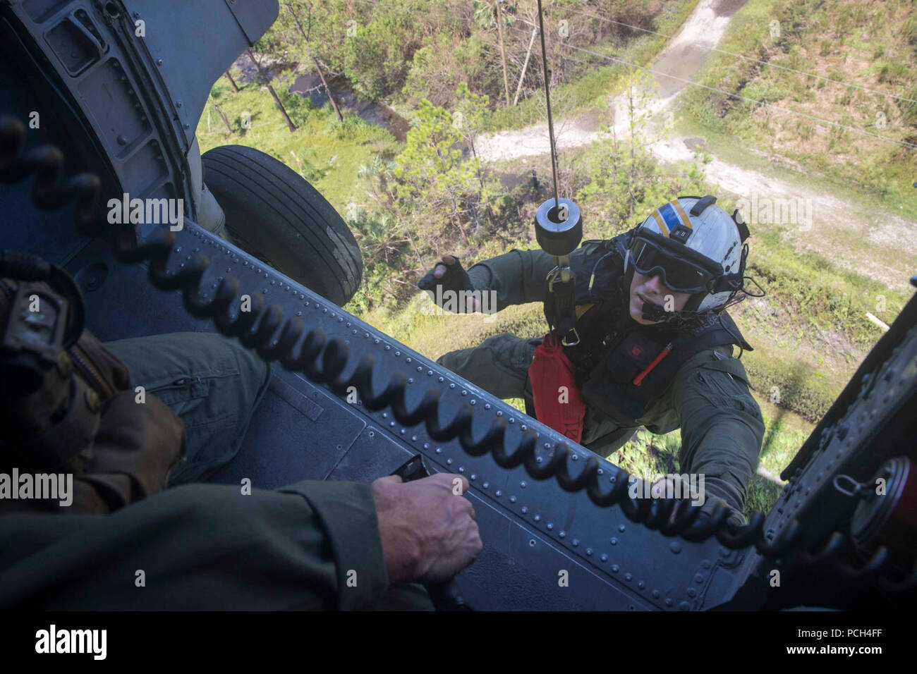 WEST, Fla. (Sept. 12, 2017) Air Crewman (Helicopter) 2nd Class Kurt Weber, from Langing, Kansas, is hoisted into an MH-60R Sea Hawk, from the Spartans of Helicopter Sea Maritime Squadron (HSM) 70, after providing aid to residents affected by Hurricane Irma . The Department of Defense is supporting Federal Emergency Management Agency, the lead federal agency, in helping those affected by Hurricane Irma to minimize suffering and is one component of the overall whole-of-government response effort. Stock Photo