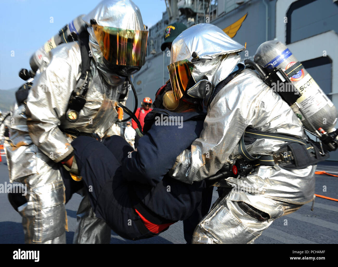Aviation Boatswain's Mate (Handling) Airman Jovoni West, left, and Aviation Boatswain's Mate (Handling) Airman Gregorio Rangel, members of the crash and salvage team, move a simulated casualty during an aircraft fire drill on the flight deck of the forward-deployed amphibious assault ship USS Bonhomme Richard (LHD 6). Bonhomme Richard is the lead ship of the Bonhomme Richard Amphibious Ready Group. Stock Photo