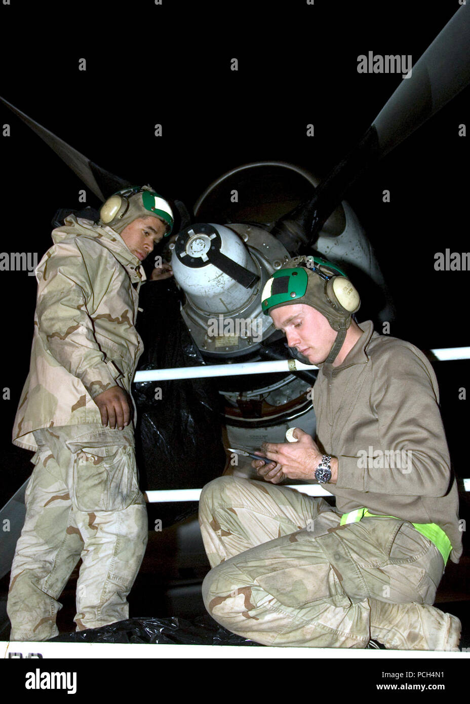 Aviation machinist's mate Airman Zechariah Edwards and aviation machinist's mate Petty Officer 3rd Class Daniel Childress perform maintenance on the engine of a P-3C Orion aircraft. Aircraft maintainers are working throughout the night to keep the planes mission ready. Stock Photo
