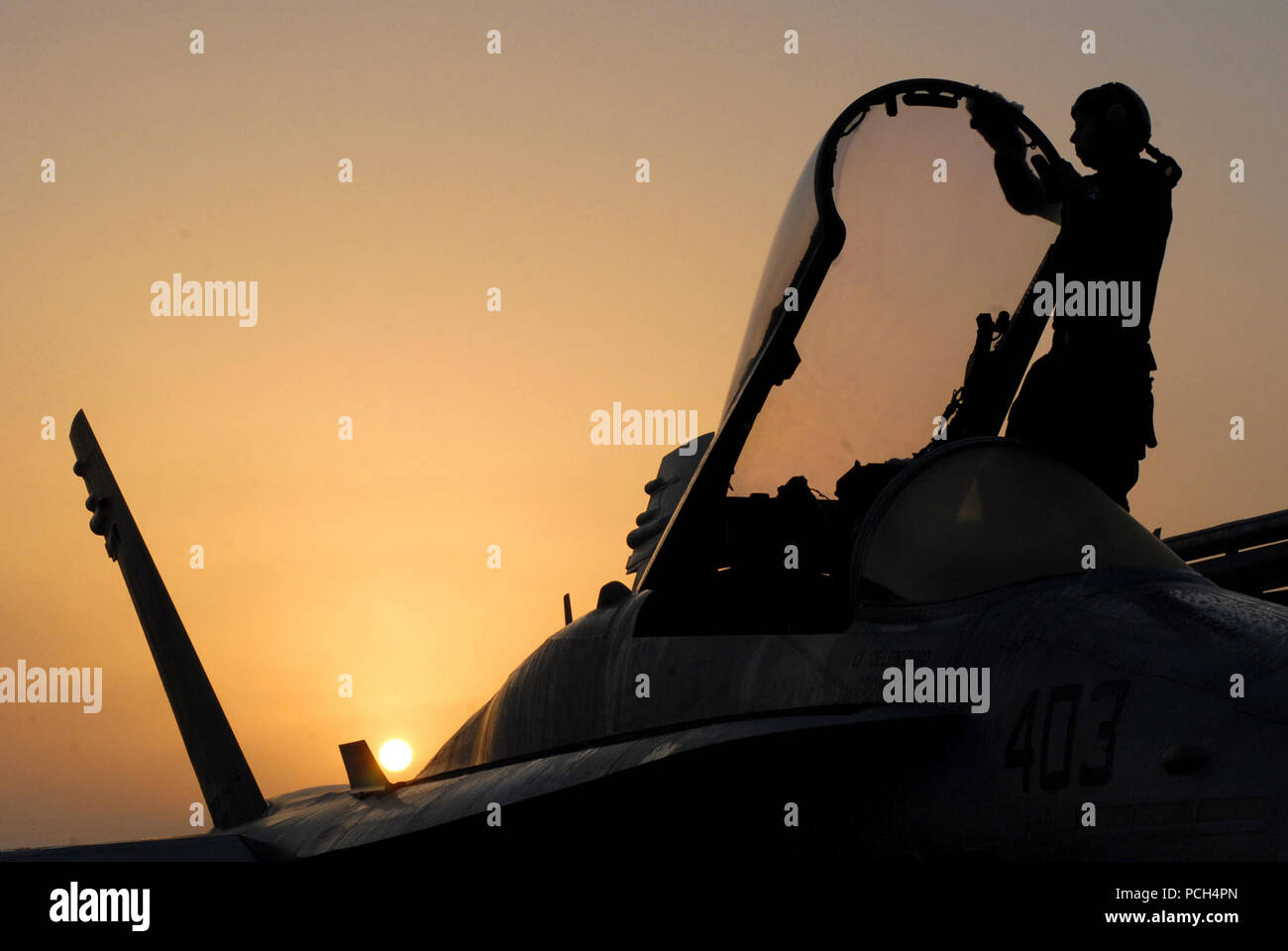 In the orange glow of the rising sun, Petty Officer 3rd Class Kyle Alhers begins the days routine of a plane captain, by wiping off the condensation formed on the canopy of an F/A-18C Hornet assigned to the 'Fist of the Fleet' of Strike Fighter Squadron 25. Plane captains are essential members of the squadron, they are ultimately in charge of making sure that their perspective aircraft is ready to fly by its designated launch time. The Nimitz-class aircraft carrier USS Ronald Reagan is currently deployed to the 5th Fleet/NAVCENT area of responsibility. Operations in the NAVCENT area of operati Stock Photo