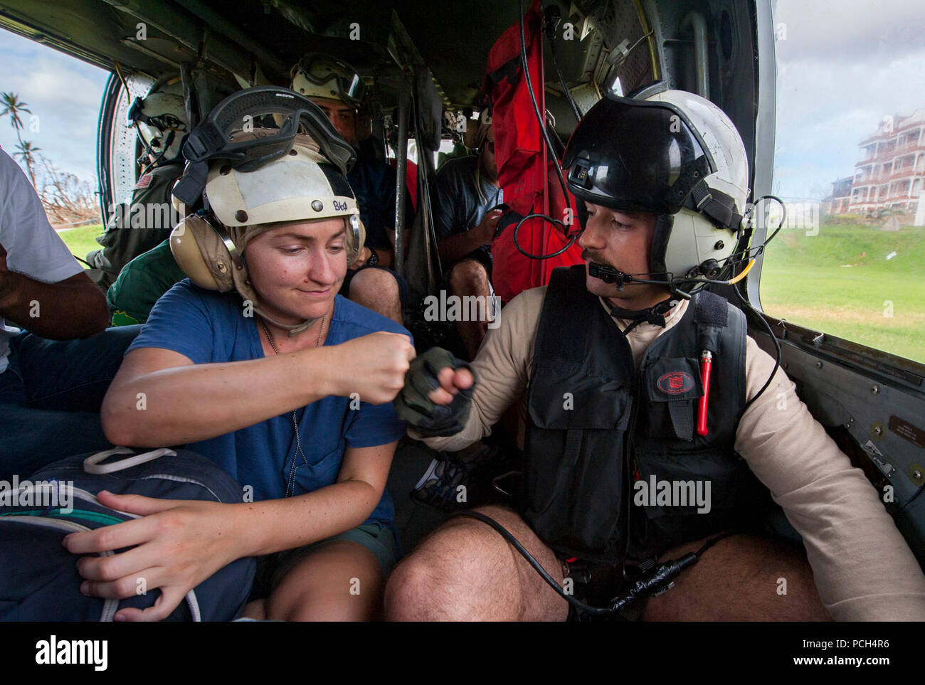 DOMINICA (Sept. 24, 2017) Naval Aircrewman (Helicopter) 2nd Class Andy Blessing "fist bumps" an evacuee on an MH-60S Sea Hawk helicopter from Helicopter Sea Combat Squadron 22 (HSC-22), attached to the amphibious assault ship USS Wasp (LHD 1), during humanitarian aid operations on the embattled island of Dominica following the landfall of Hurricane Maria. The Department of Defense is supporting United States Agency for International Development (USAID), the lead federal agency, in helping those affected by Hurricane Maria to minimize suffering and is one component of the overall whole-of-gover Stock Photo
