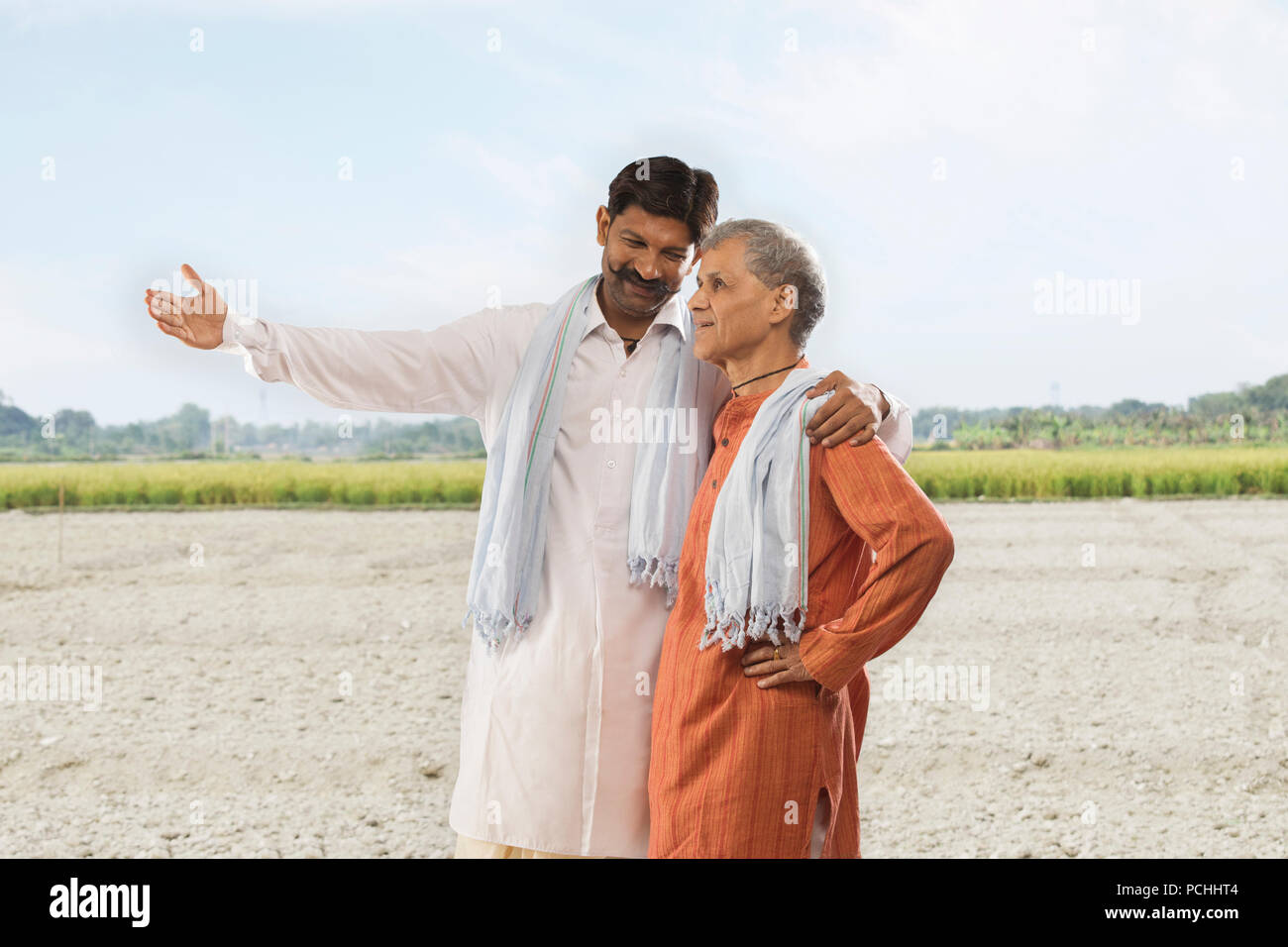Farmer showing paddy field to his father Stock Photo