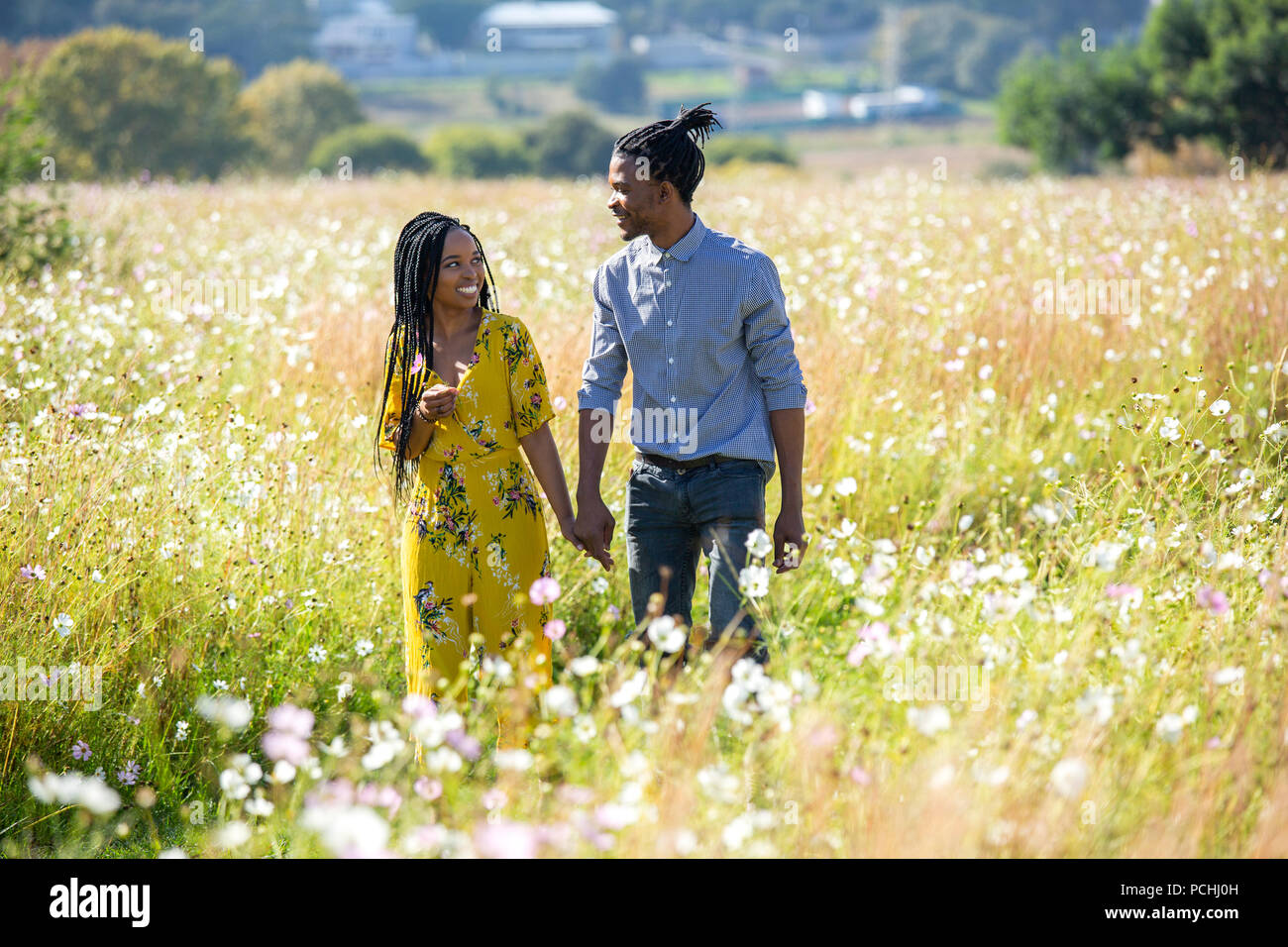 Couple holding hands walking in field Stock Photo