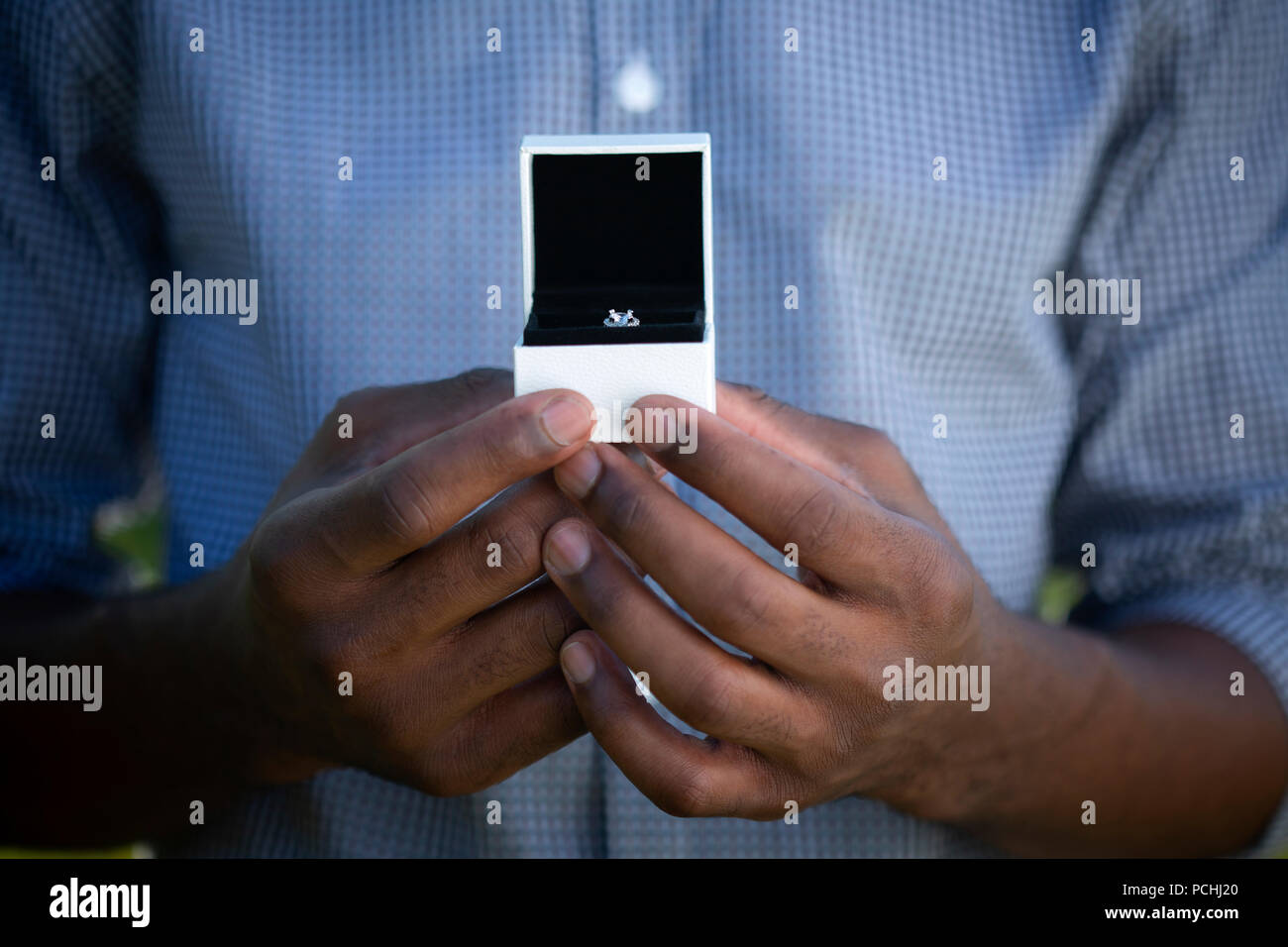 African man holding engagement ring in box Stock Photo