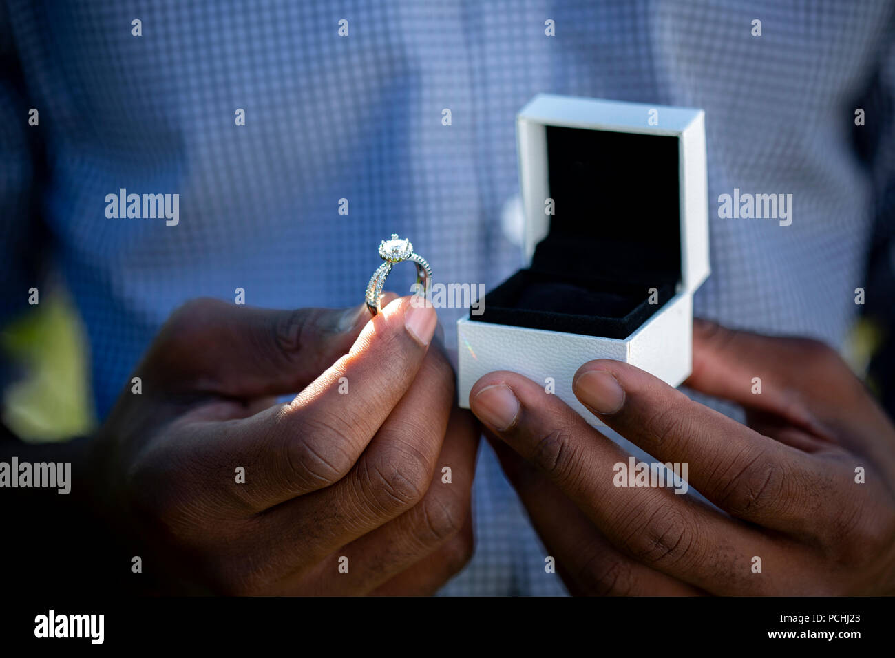 African man holding engagement ring and box Stock Photo