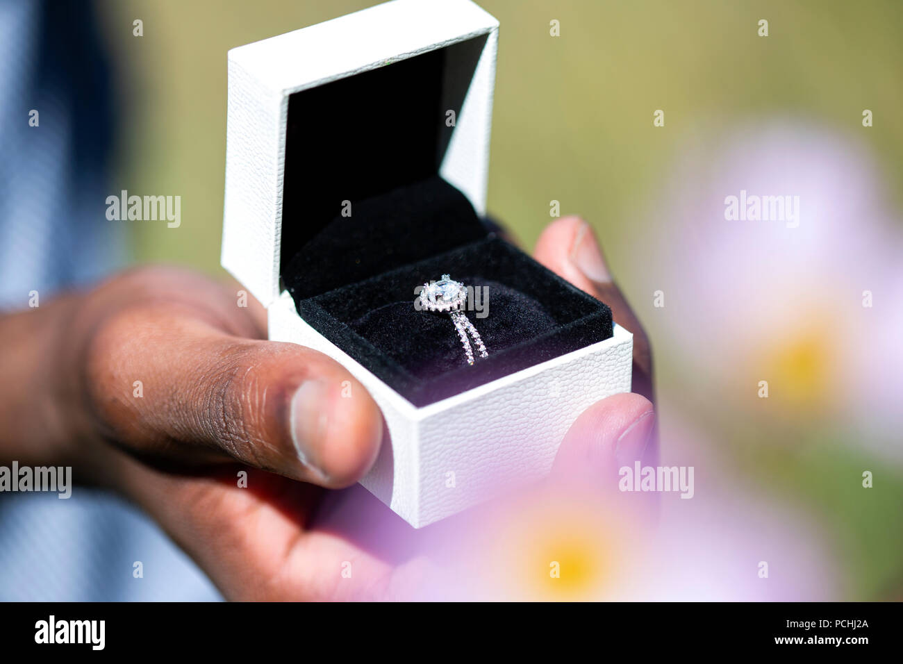 African man holding engagement ring in box Stock Photo