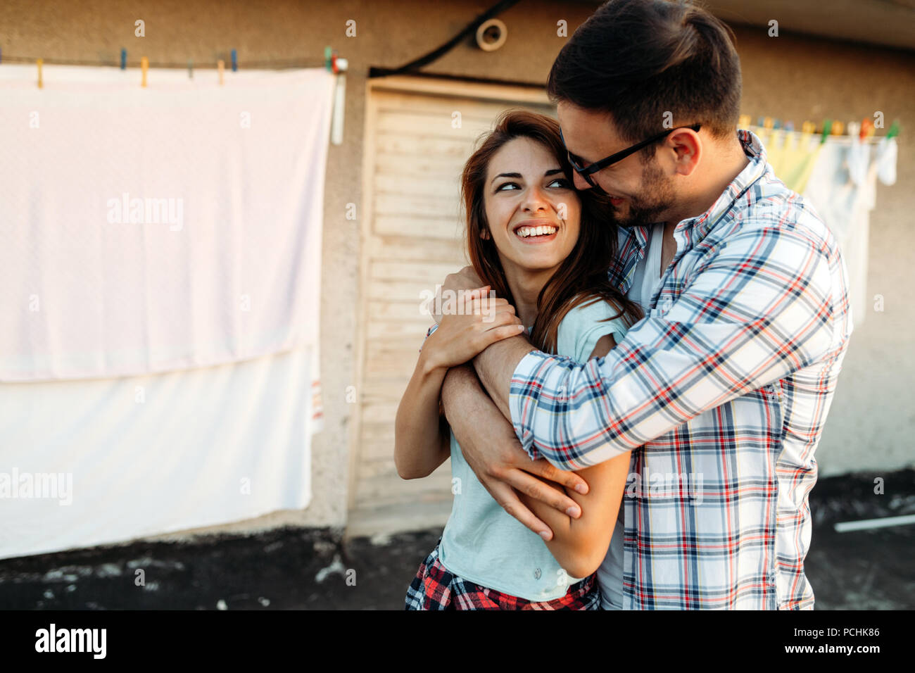 Portrait of a loving young man embracing woman from behind Stock Photo ...
