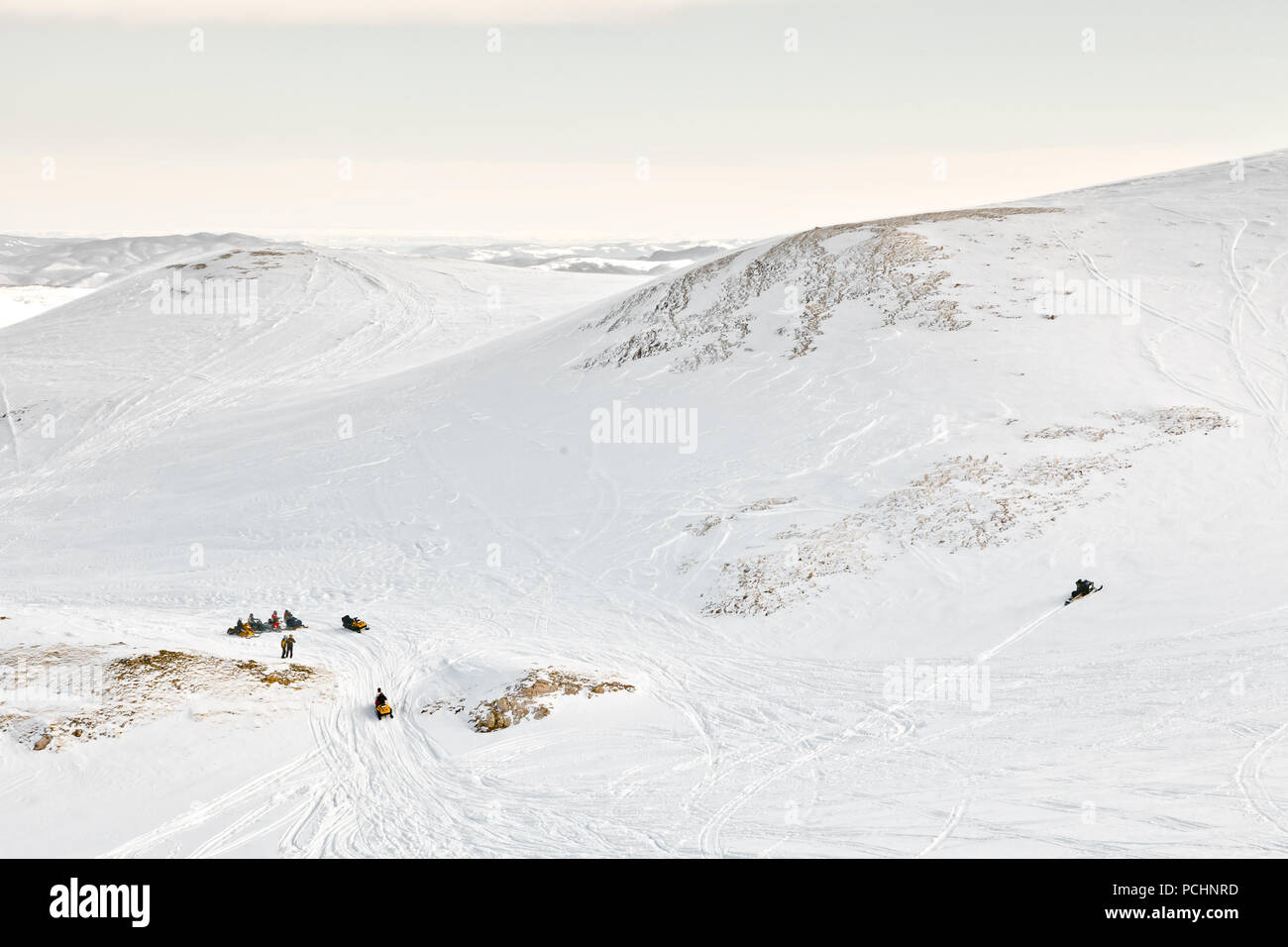 Riders snowmobile in snow-covered hills in the State Nature Reserve in Adygea, Russia. Stock Photo