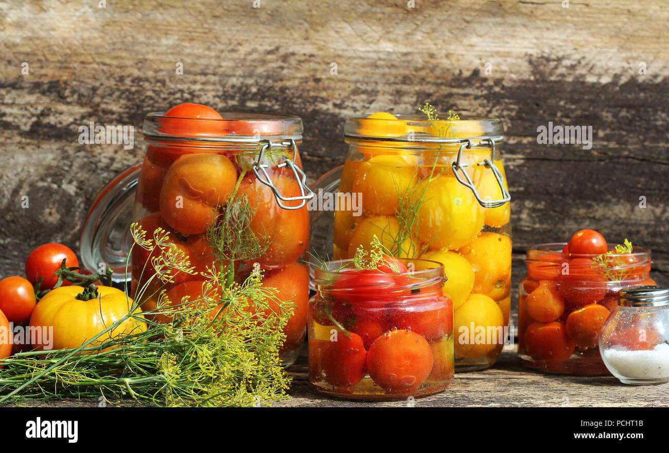 Pickled tomato in jars on wooden table . Tomatoes fermented process
