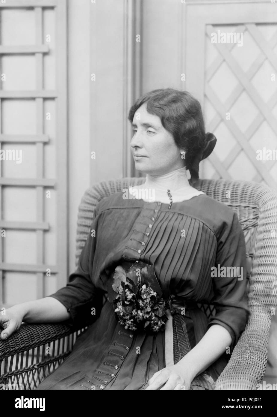 Helen Keller, seated looking left with flower at the International Flower Show April 1913 in New York City, New York. Helen Keller (June 27, 1880 – June 1, 1968) was an American author, political activist, and lecturer. She was the first deaf-blind person to earn a bachelor of arts degree. Stock Photo