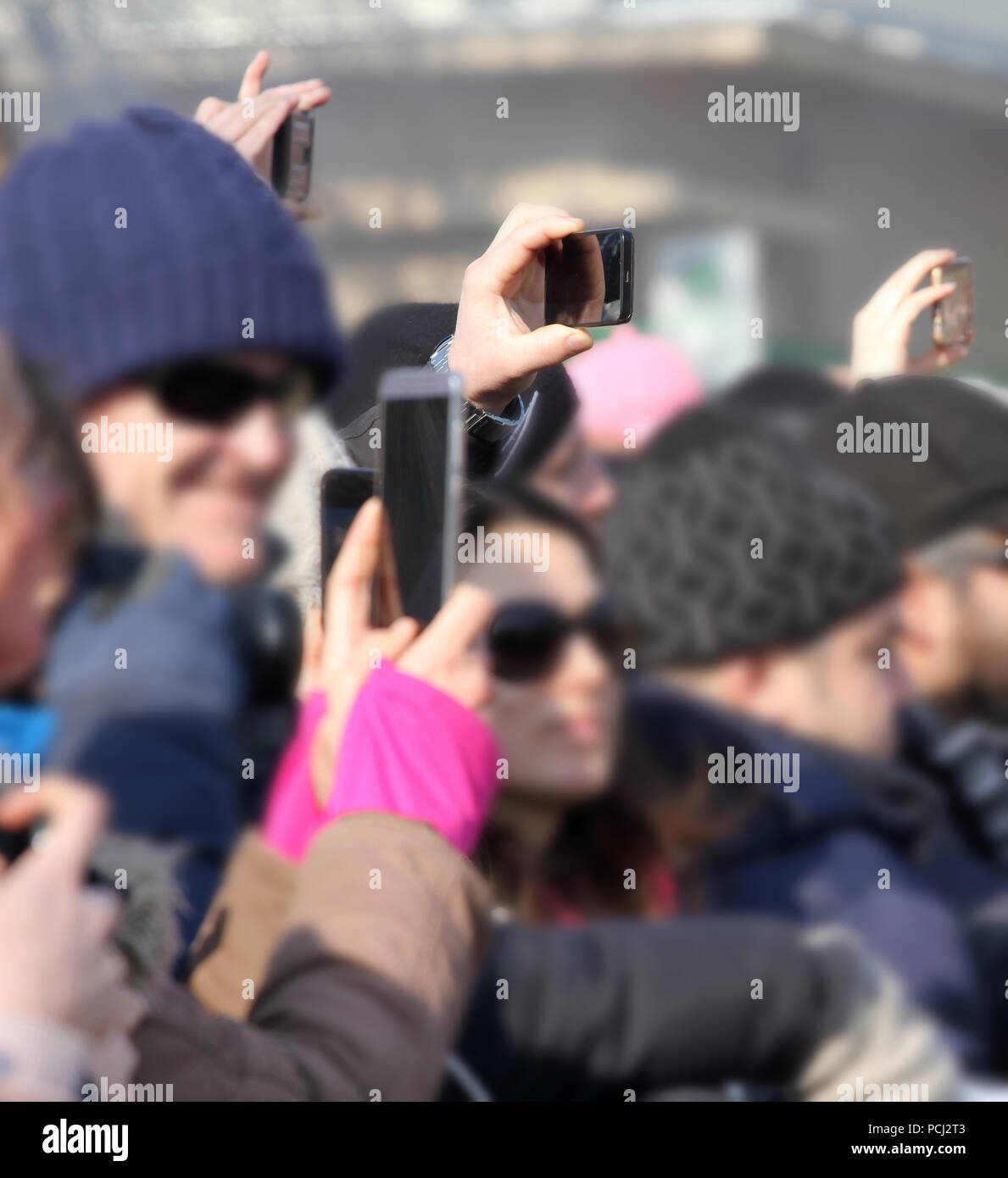 A blurred crowd of people use different types of smart phones and tablets to take a pictures of interesting things . Many phones in one place. smart d Stock Photo