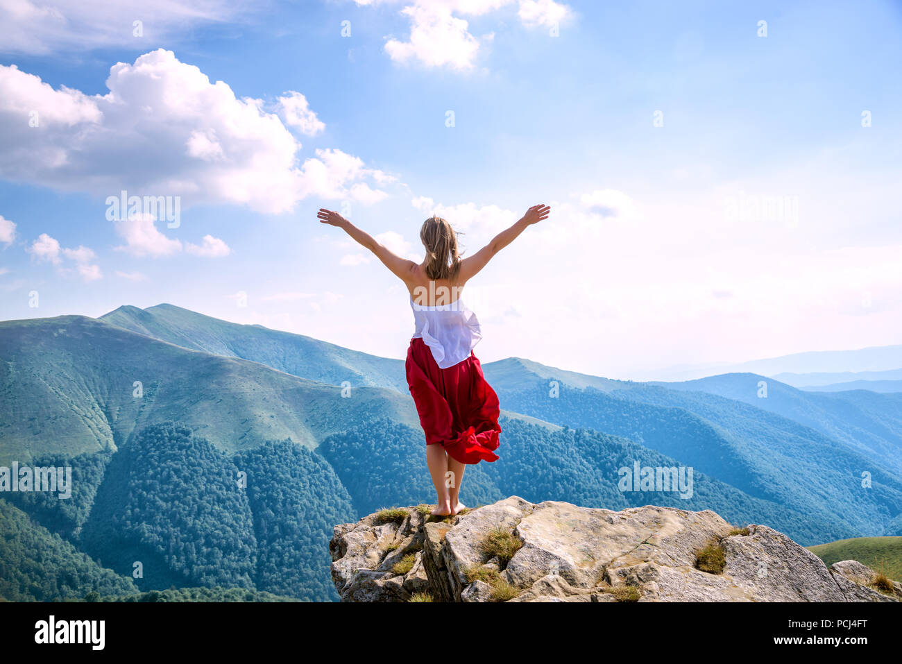 Young woman in red dress staying on the top of mountain Stock Photo - Alamy