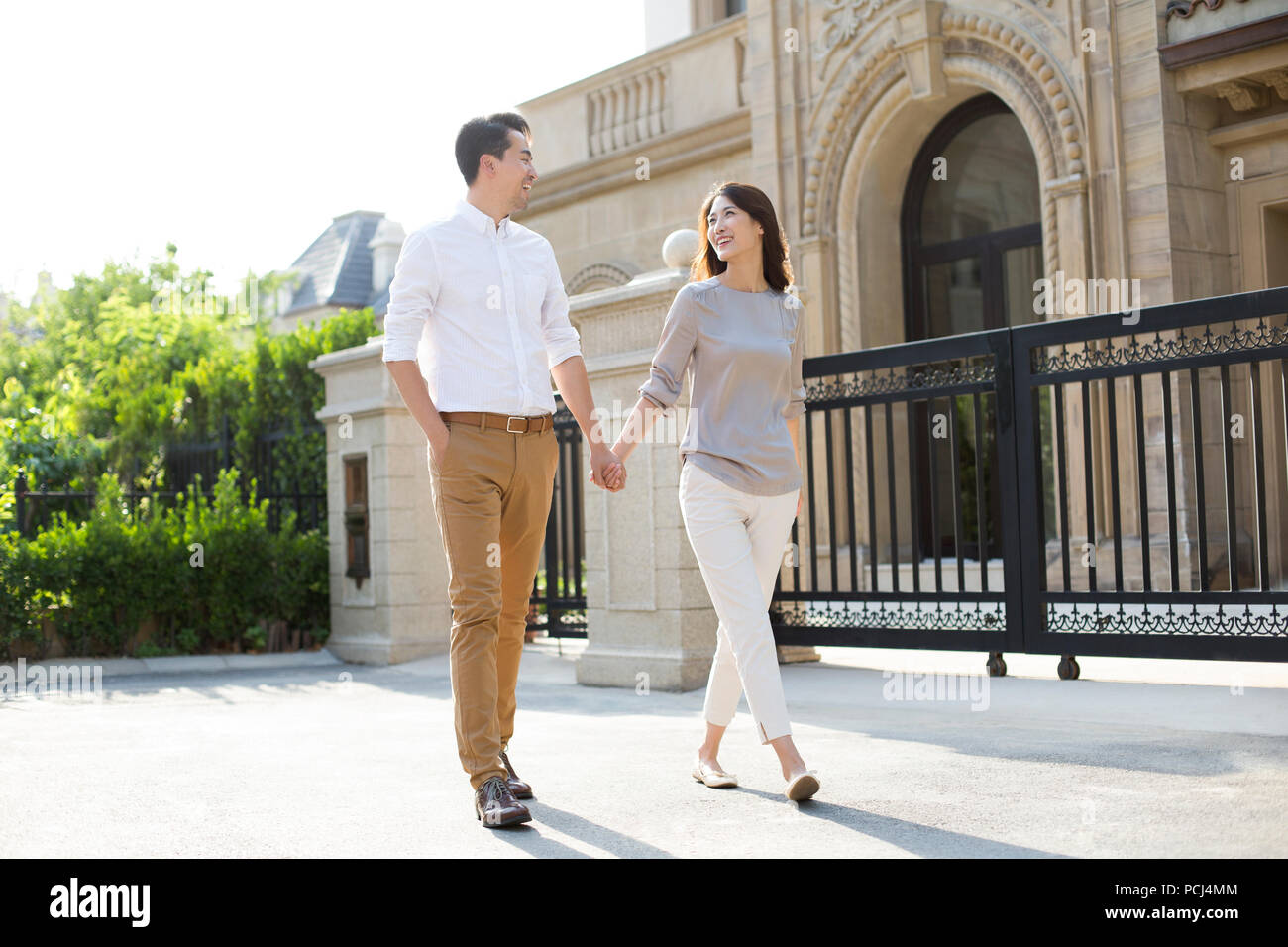 Cheerful young Chinese couple holding hands walking Stock Photo - Alamy
