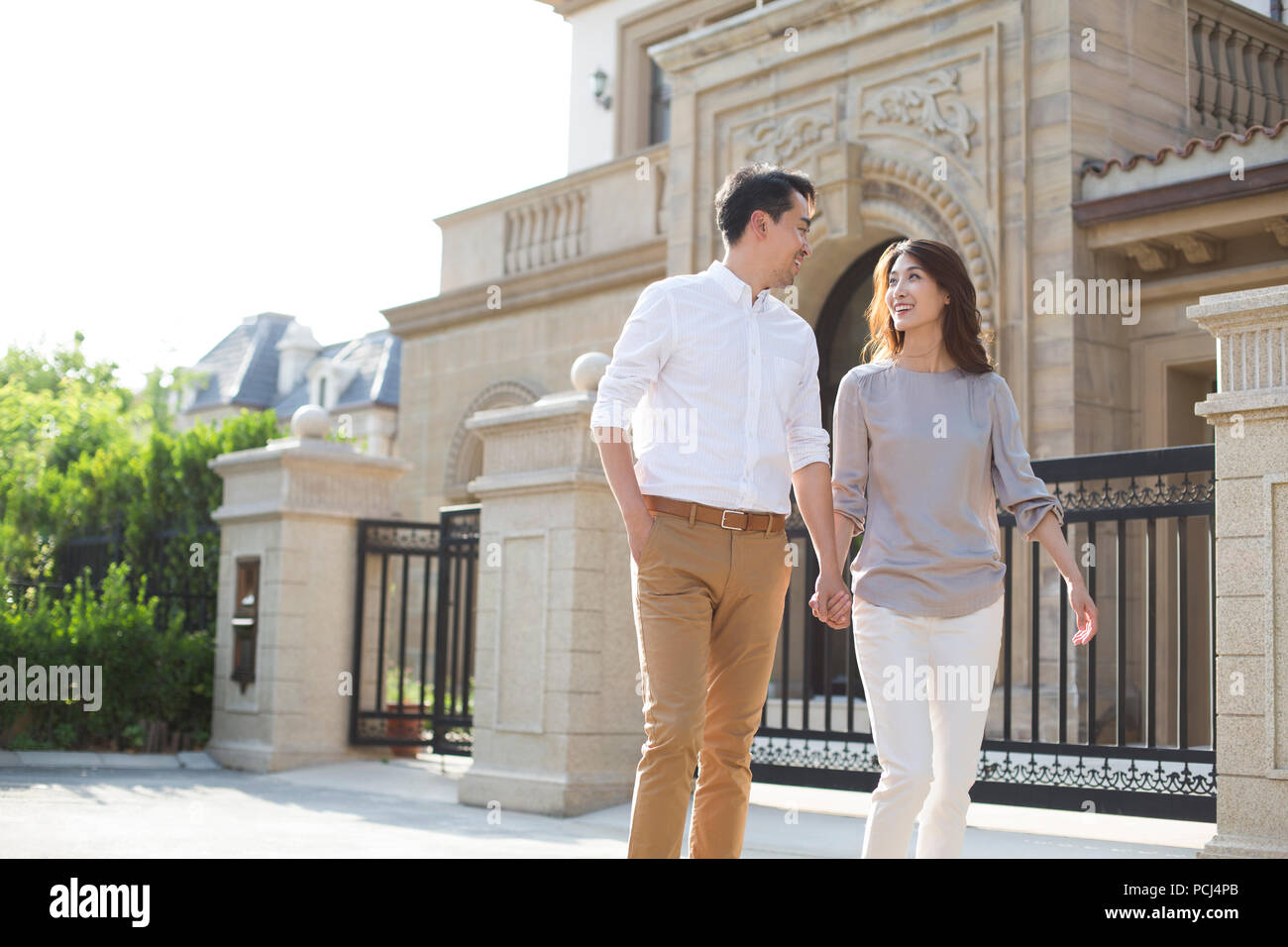 Cheerful young Chinese couple holding hands walking Stock Photo