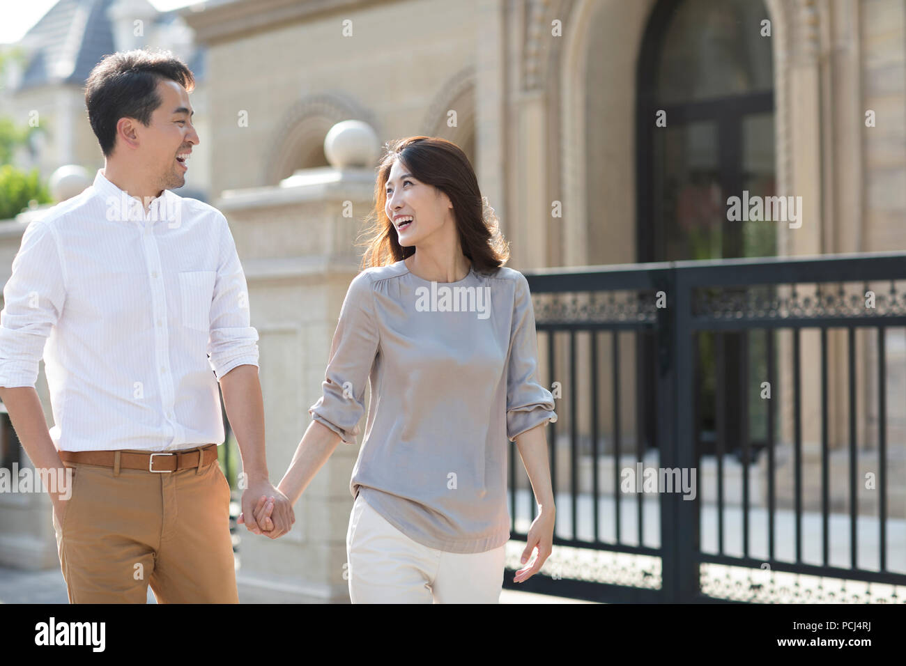 Cheerful young Chinese couple holding hands walking Stock Photo - Alamy
