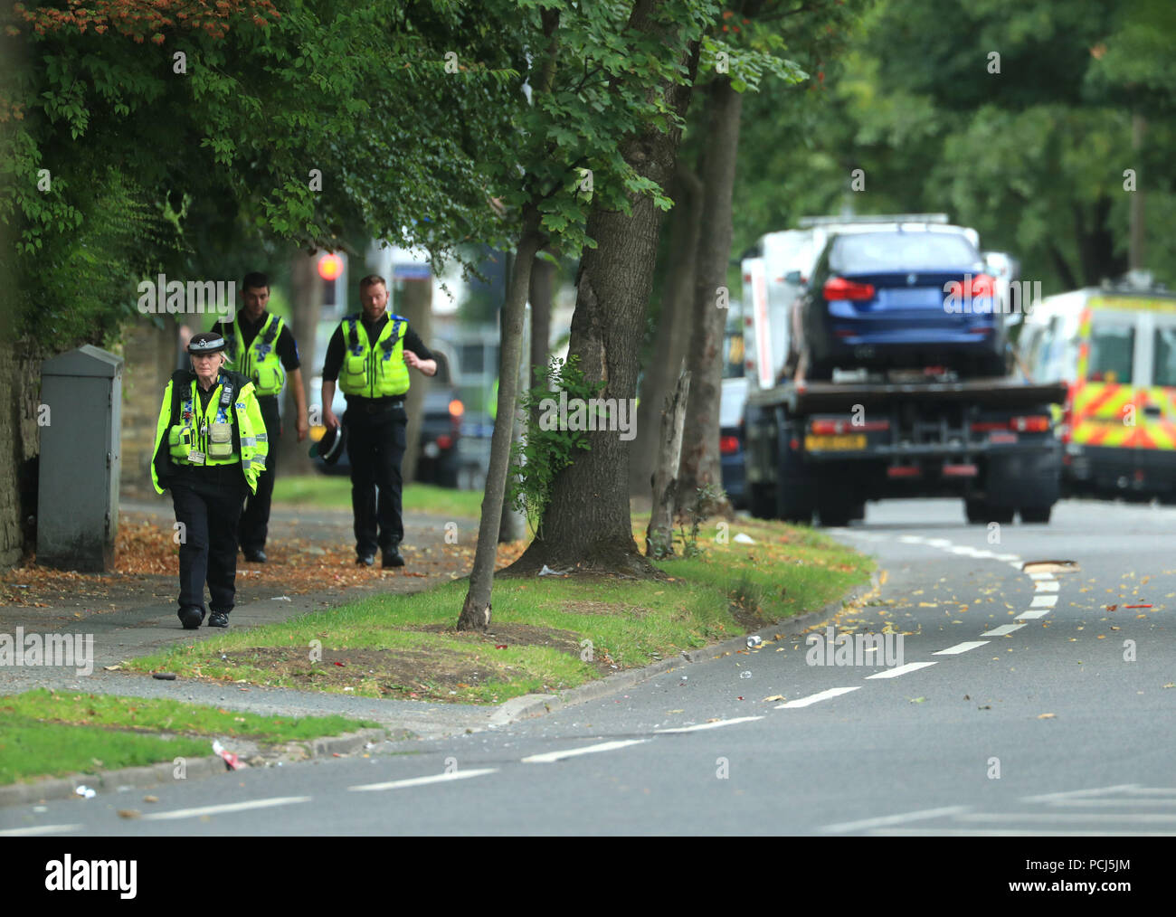 Police officers near the scene on Bingley Road at the junction with Toller Lane in Bradford following a road traffic collision where four males died in a car which was being followed by an unmarked police vehicle when it crashed. Stock Photo