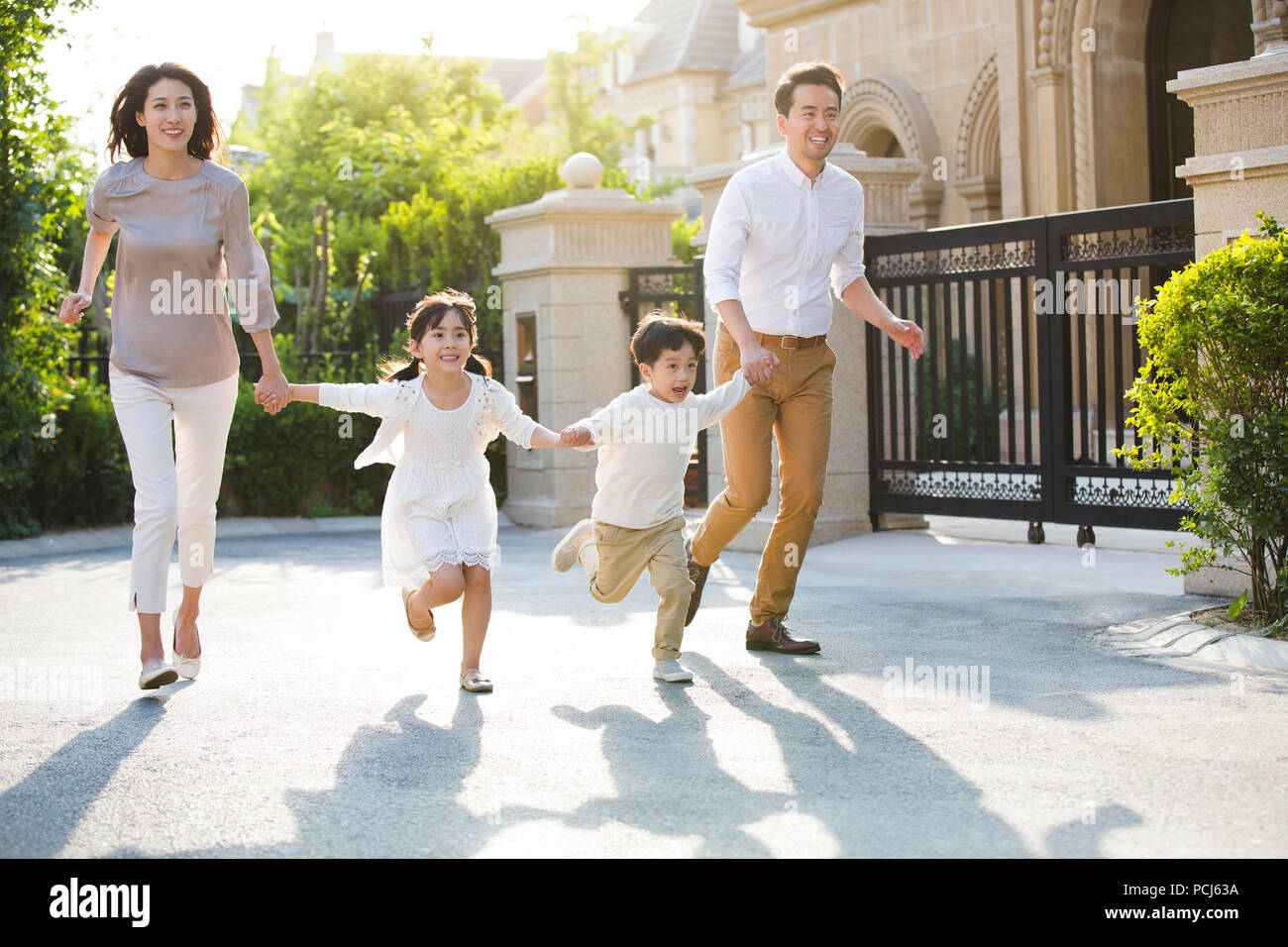 Happy young Chinese family holding hands running Stock Photo