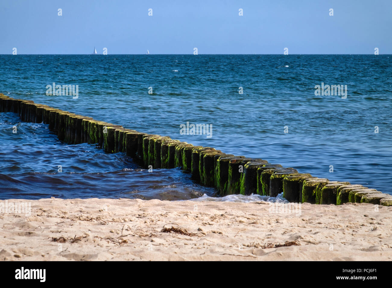 Germany Loddin,Stubbenfelde Beach. Coastal bathing resort on the island of Usedom on the Baltic Sea. Sandy beach, algae-covered groyne,blue sea & sky  Stock Photo