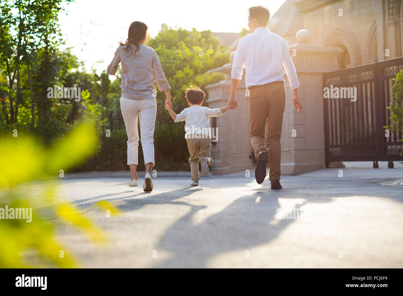 Happy young Chinese family holding hands running Stock Photo - Alamy