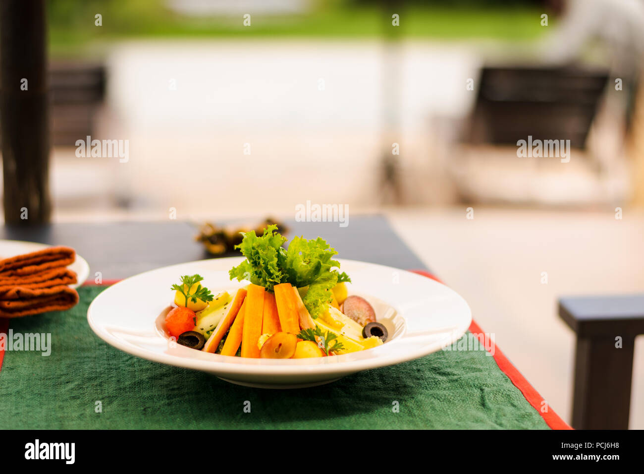 Vegetarian entrée for lunch meal with fresh carrot, salad, grape, olive, watermelon, served in a dish of a terrace. Stock Photo