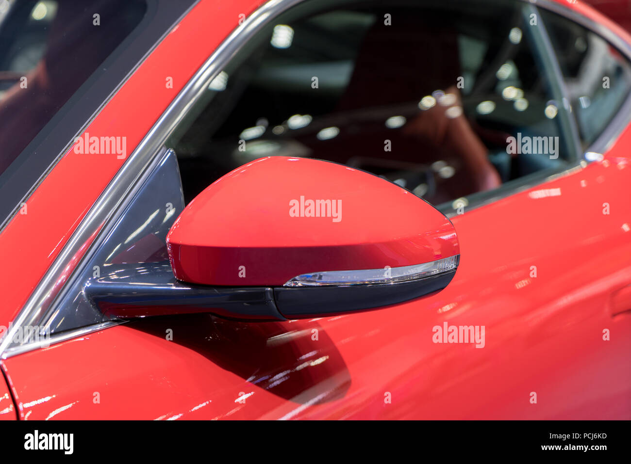 Red side view mirror with red sport modern car. Stock Photo