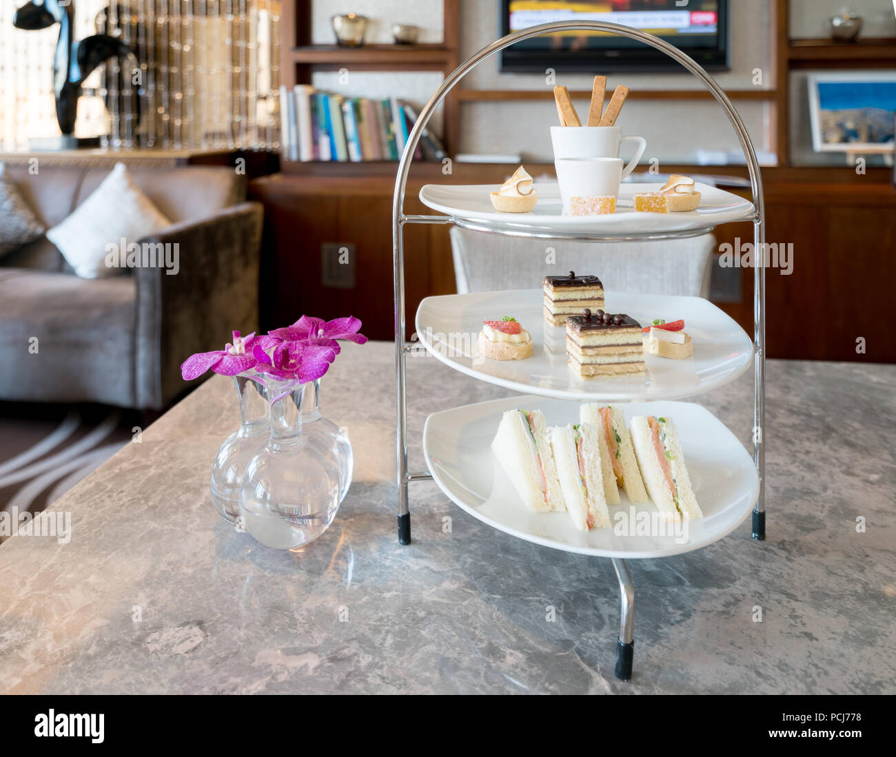 Afternoon tea with ham sandwich chocolate cake and other snack in white plate at lounge in hotel. Stock Photo