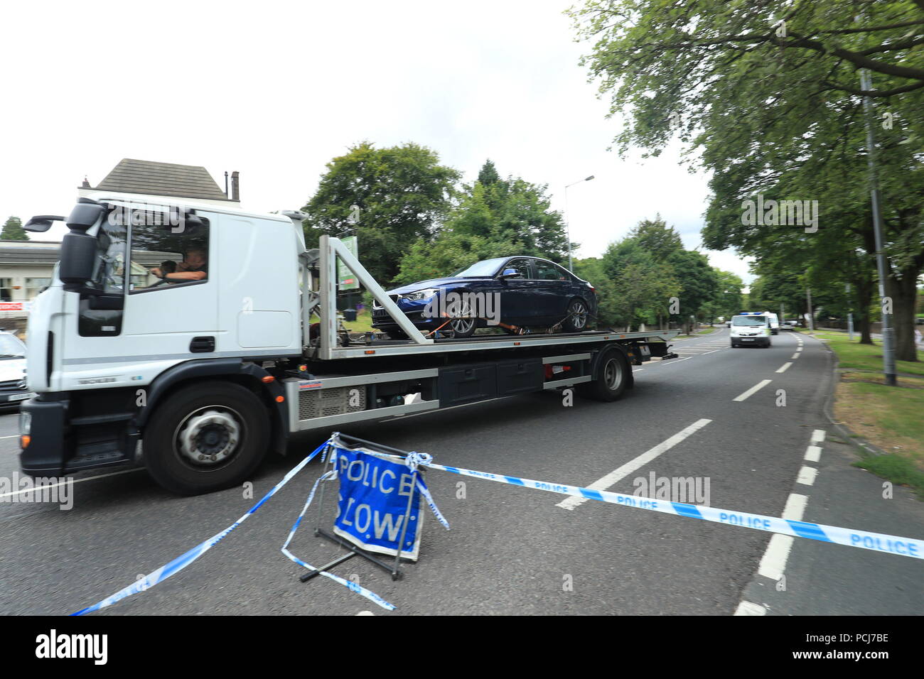 A vehicle is removed from the scene on Bingley Road at the junction with Toller Lane in Bradford following a road traffic collision where four males died in a car which was being followed by an unmarked police vehicle when it crashed. Stock Photo