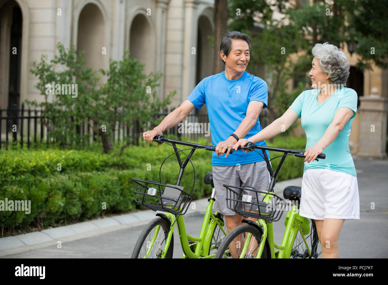 Cheerful senior Chinese couple with sharing bikes Stock Photo