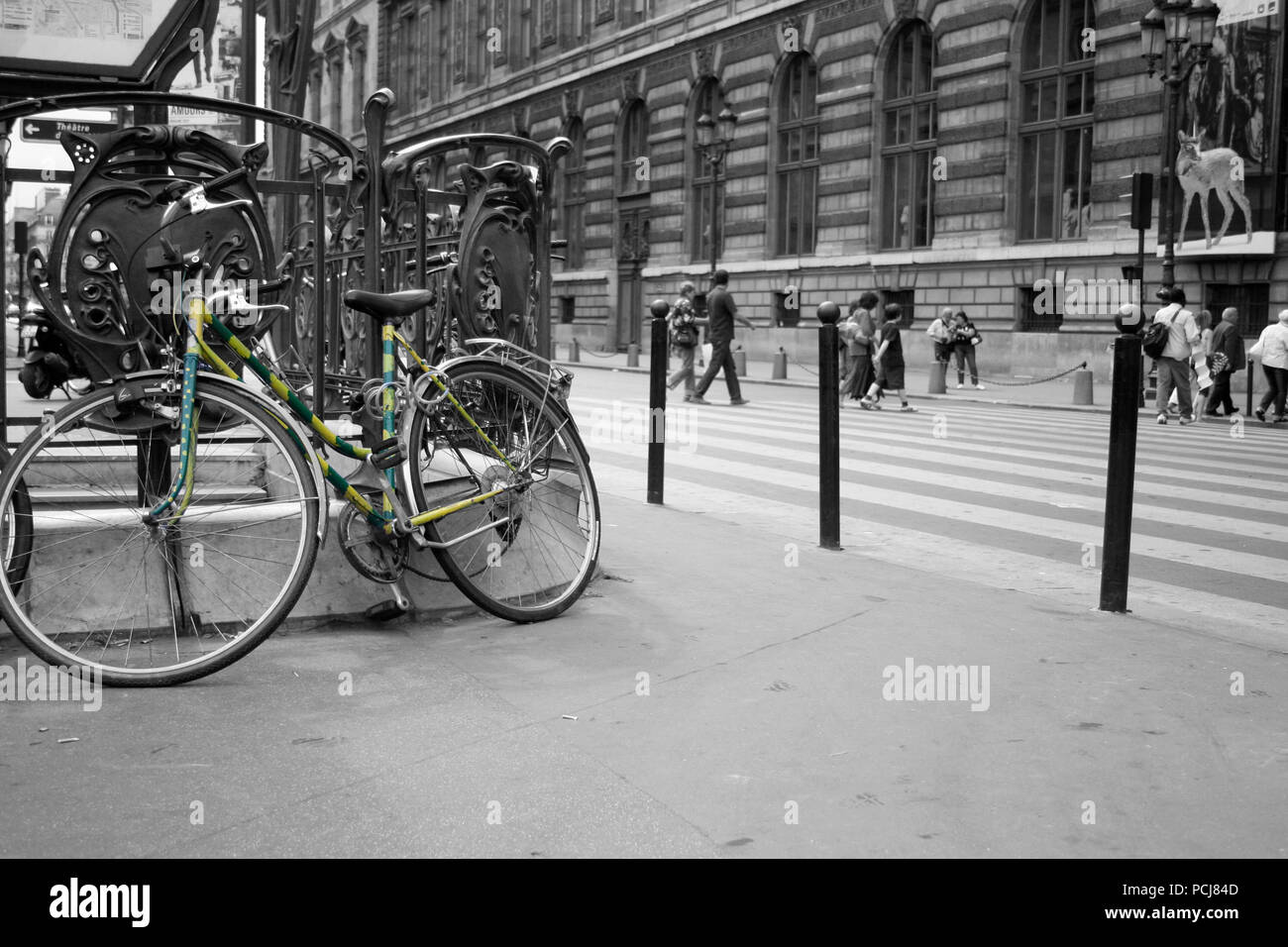 Green and yellow striped bicycle outside Métro Palais Royal - Musée du Louvre metro station in Paris colour picked on black and white Stock Photo