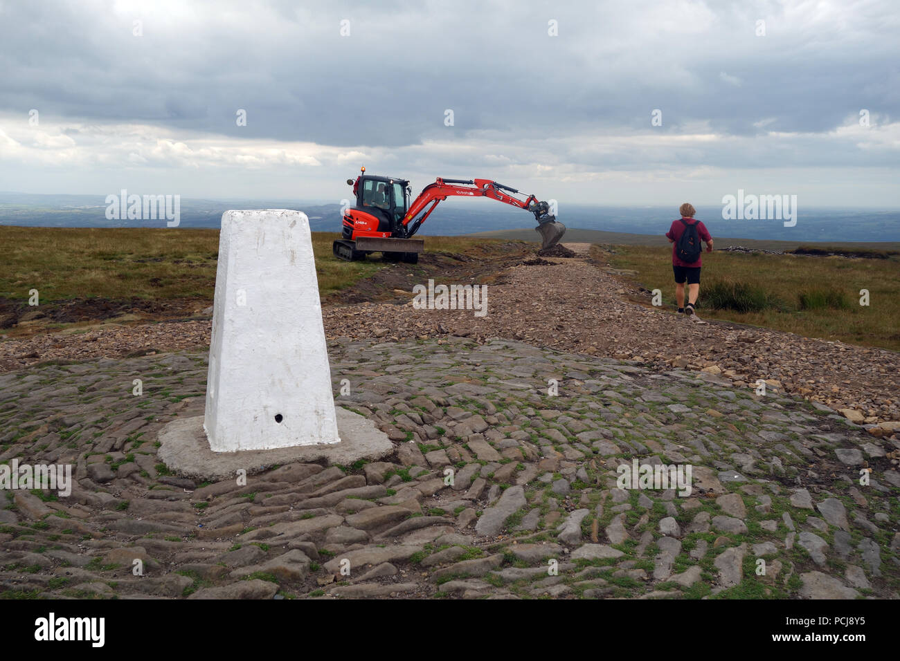 Man Walking near Digger Working on the New Path Being Constructed Leading up to the Trig Column on the Summit of Pendle Hill, Lancashire, England, UK Stock Photo