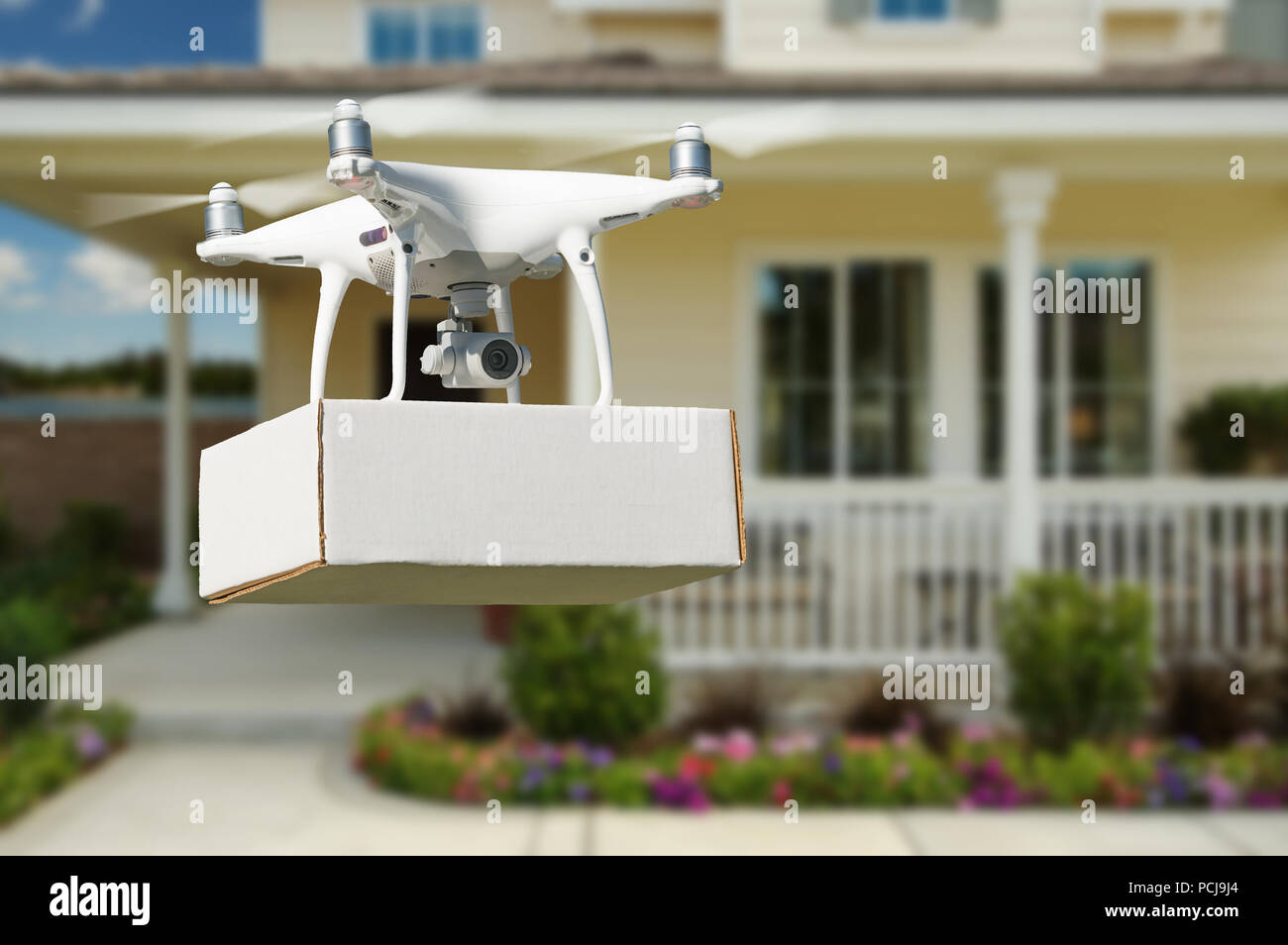 Unmanned Aircraft System (UAV) Quadcopter Drone Delivering Package At House. Stock Photo