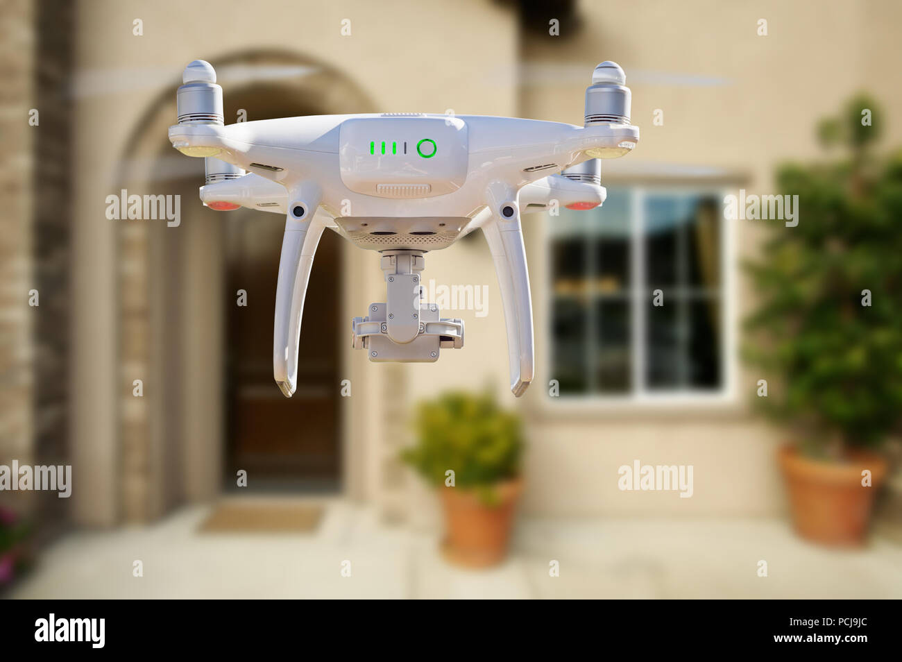 Back of Unmanned Aircraft System (UAV) Quadcopter Drone Flying In Front of House. Stock Photo
