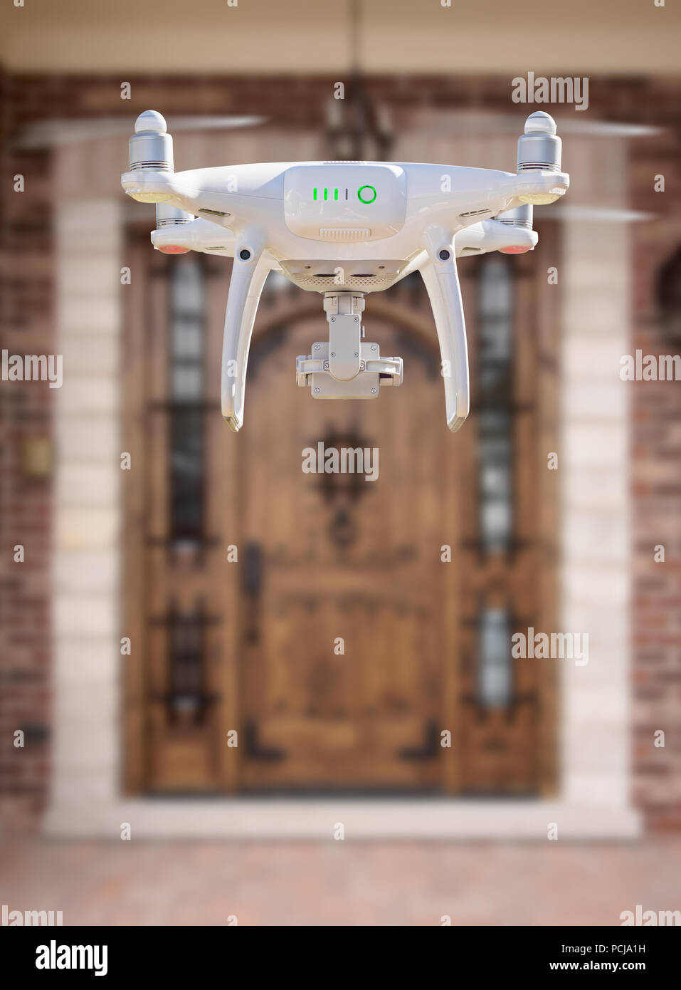 Back of Unmanned Aircraft System (UAV) Quadcopter Drone Flying At The Front Door of House. Stock Photo