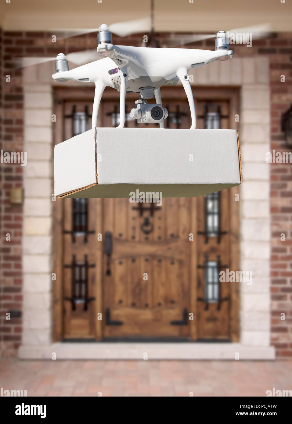 Unmanned Aircraft System (UAV) Quadcopter Drone Delivering Package At House. Stock Photo