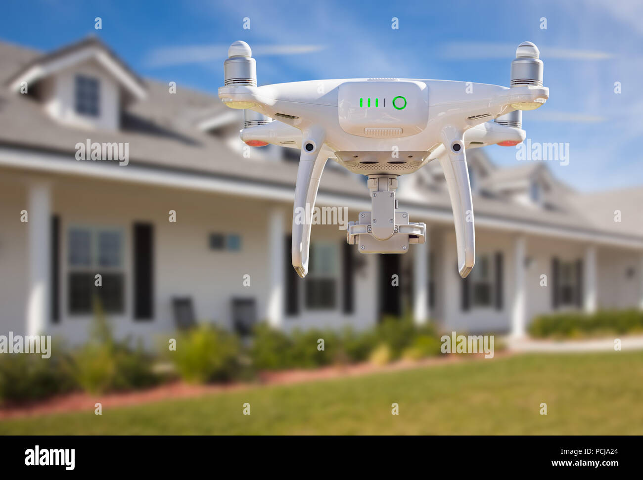 Back of Unmanned Aircraft System (UAV) Quadcopter Drone Flying In Front of House. Stock Photo