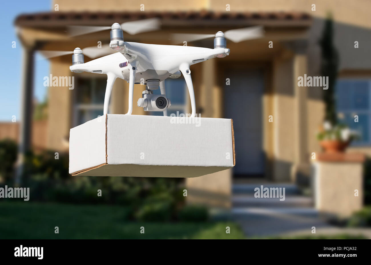 Unmanned Aircraft System (UAV) Quadcopter Drone Delivering Package At House. Stock Photo