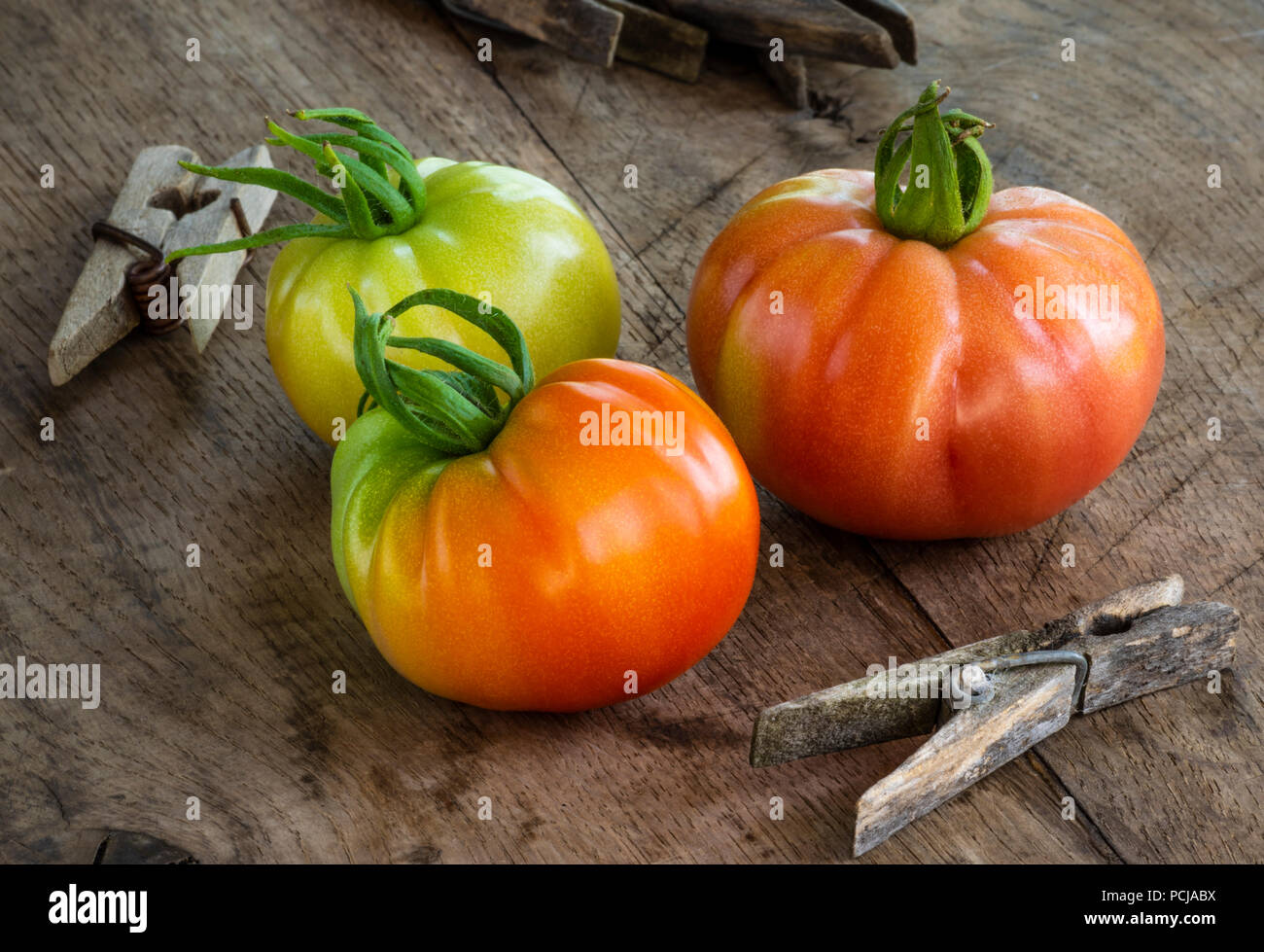 Three organic tomatoes on old wooden table Stock Photo - Alamy