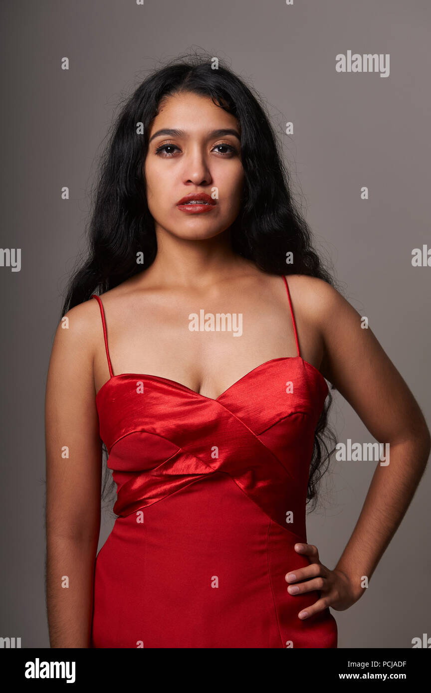 Studio portrait session of 17 years old teenager girl wearing a red dress on a grey background Stock Photo
