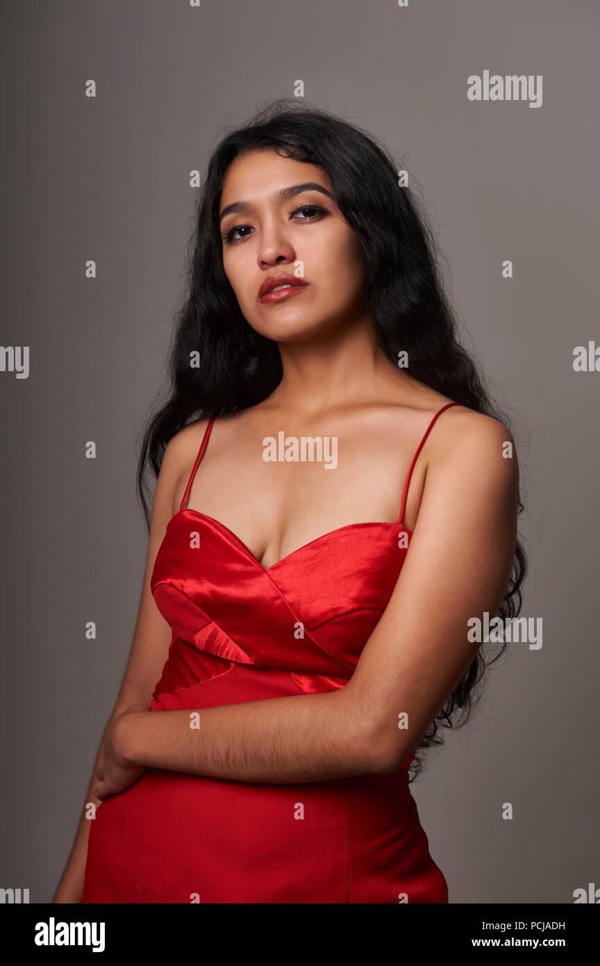 Studio portrait session of 17 years old teenager girl wearing a red dress on a grey background Stock Photo