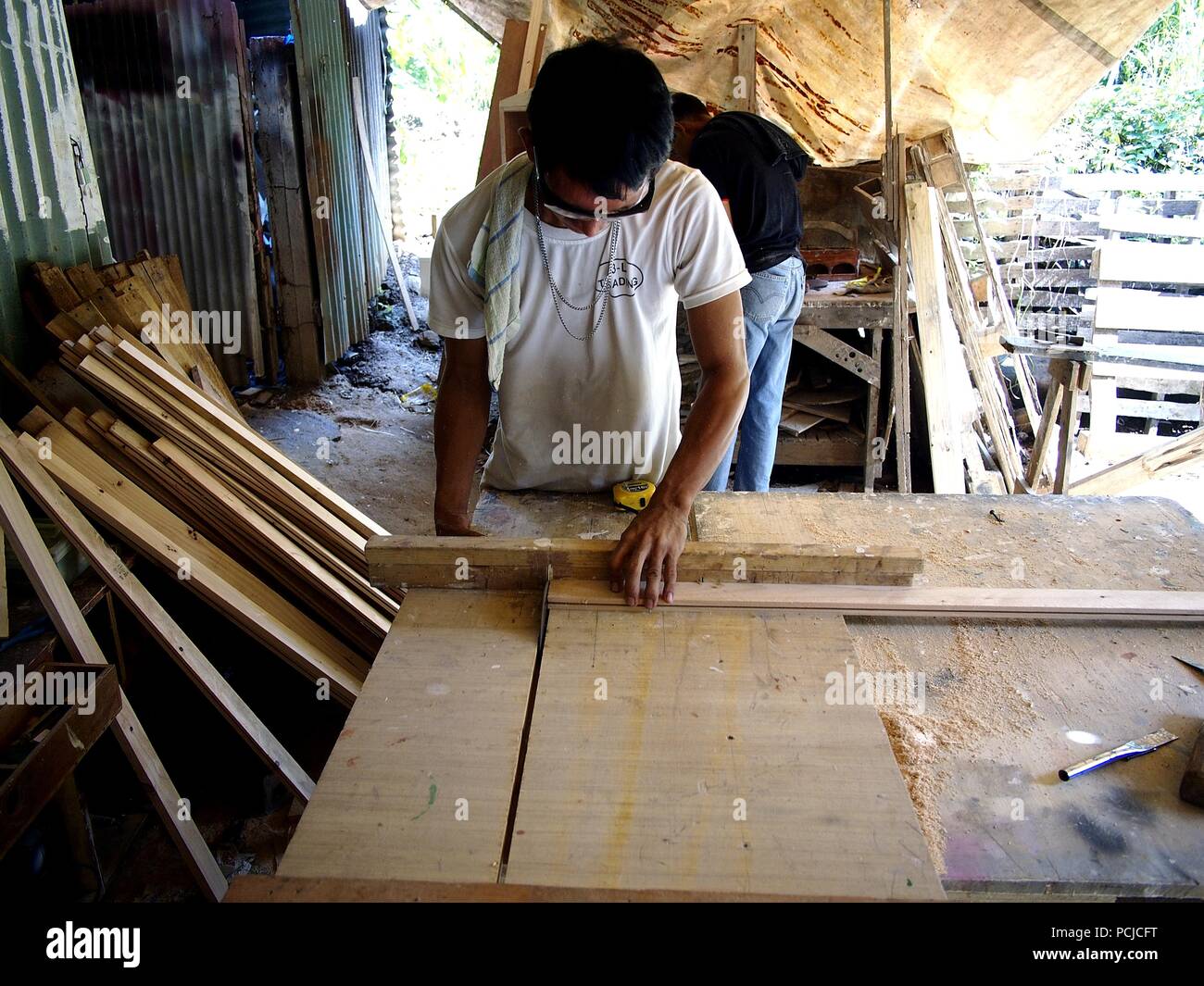 ANTIPOLO CITY, PHILIPPINES JULY 31, 2018 A carpenter cuts wood using a table saw in his