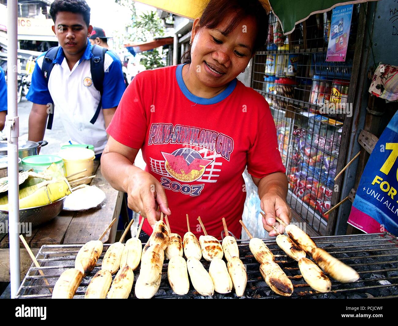 ANTIPOLO CITY, PHILIPPINES - AUGUST 1, 2018: A woman sells grilled Filipino plantain or fat banana or more known locally as Saba banana at her makeshi Stock Photo