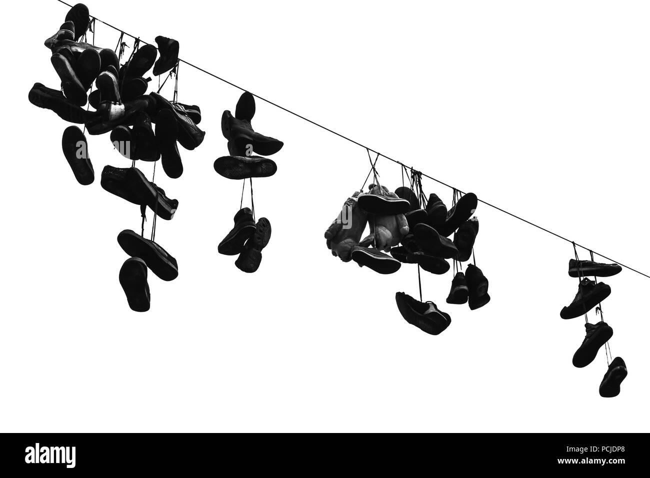 Sporty shoes hanging on electric wire, black and white photo isolated on white background Stock Photo