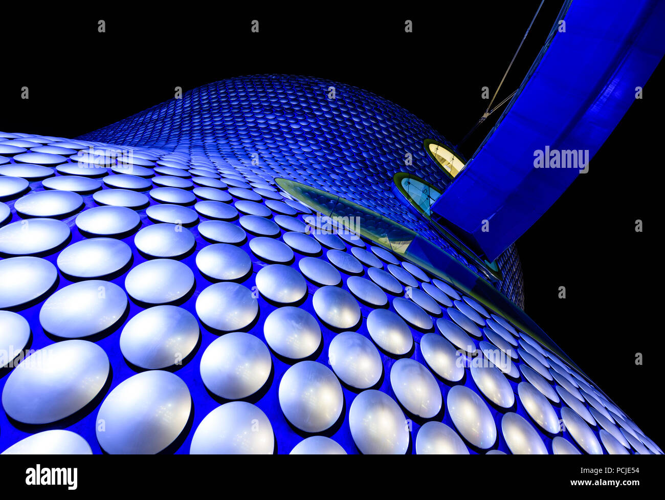 Looking up at the Selfridges building in Birmingham lit up with blue light at night and resembling a dalek from Dr Who Stock Photo