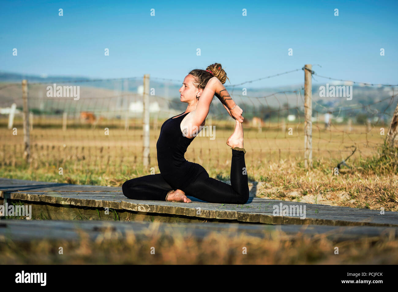 Woman on Los Lances beach doing a king pigeon yoga pose, The Strait Natural Park, Tarifa, Cadiz, Andalusia, Spain Stock Photo