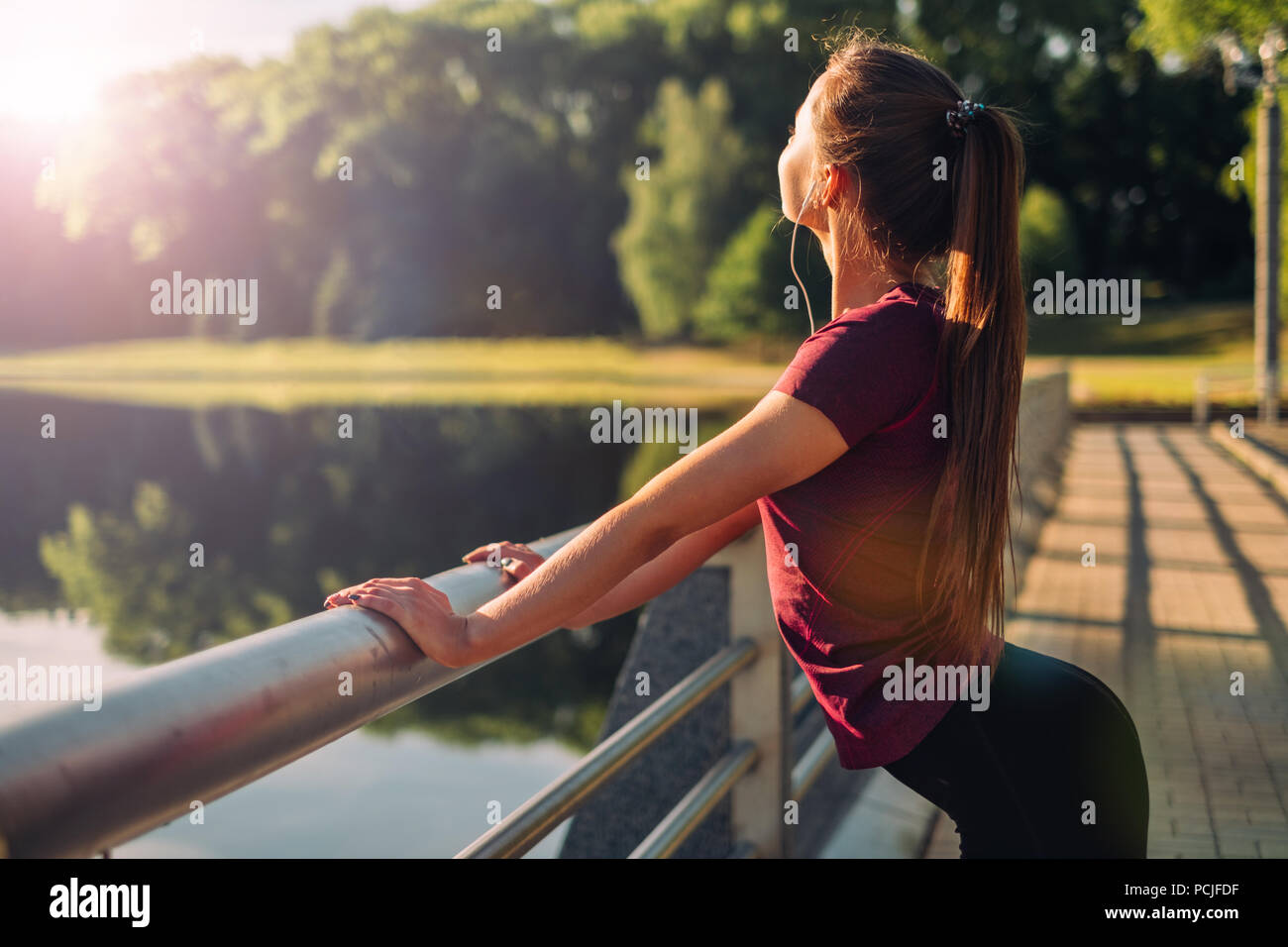 Jogger leaning against a railing listening to music Stock Photo