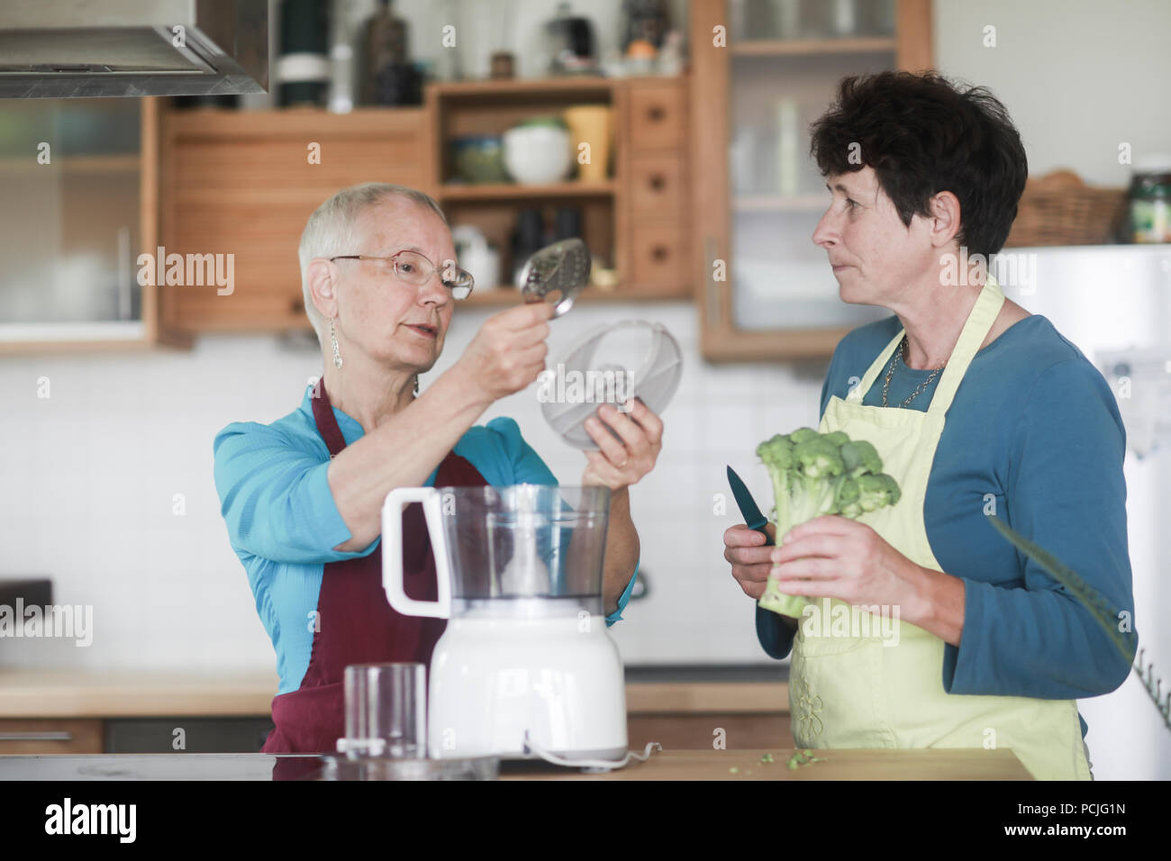 Two women standing in the kitchen preparing broccoli Stock Photo