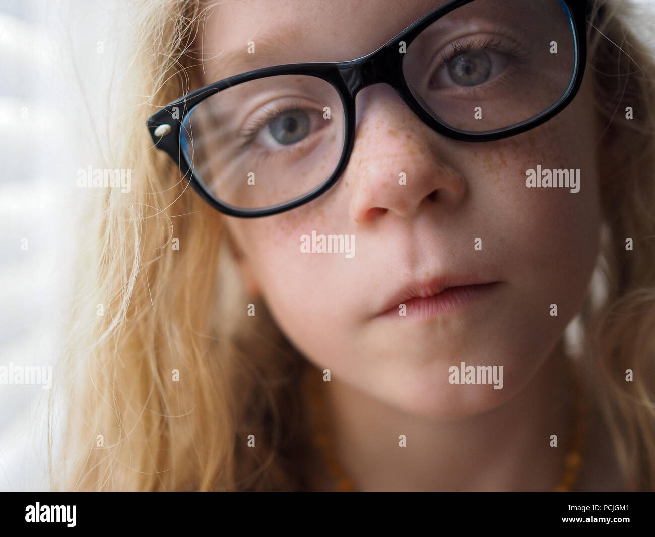 Portrait of a blonde girl with freckles wearing glasses Stock Photo