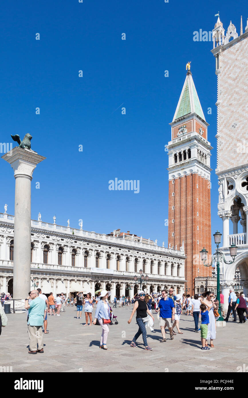 Tourists in Piazzetta San Marco with Doges Palace, Marciana Library, winged lion of St Mark on its column,   and St Marks Campanile, Venice, Veneto, I Stock Photo